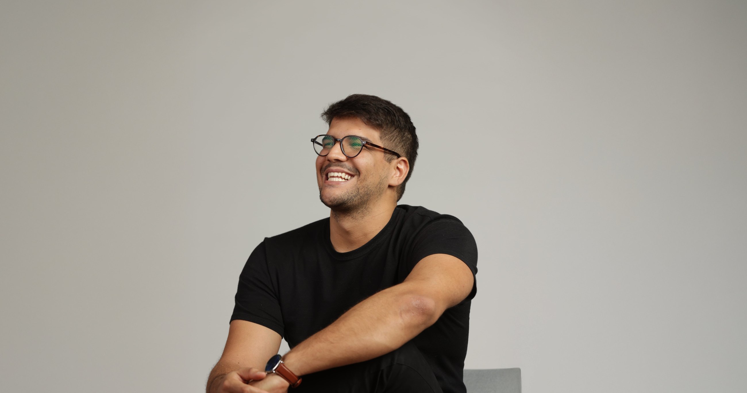 Mateus Franzé, the designer behind Franzé Studio, smiling in a black t-shirt against a grey wall